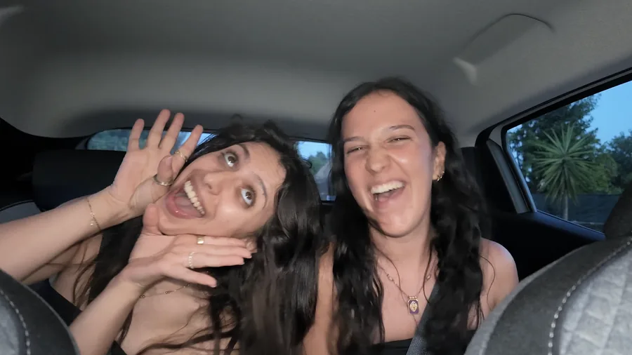 Duas pessoas a rir dentro de um carro, a olhar para a câmara