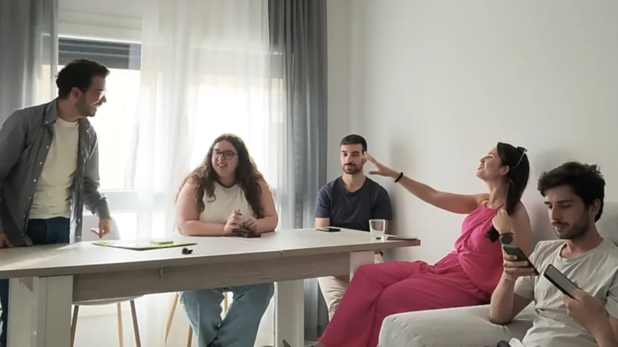 Cinco pessoas numa sala à volta de uma mesa, a conversar durante uma reunião de equipa